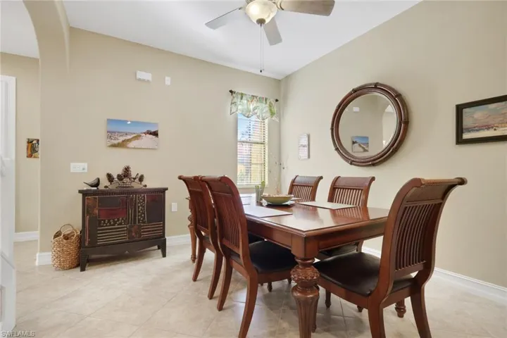 Dining area with arched walkways, ceiling fan, and light tile patterned floors
