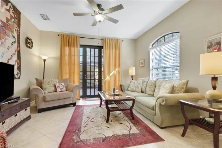 Living room featuring healthy amount of natural light, light tile patterned floors, and a ceiling fan