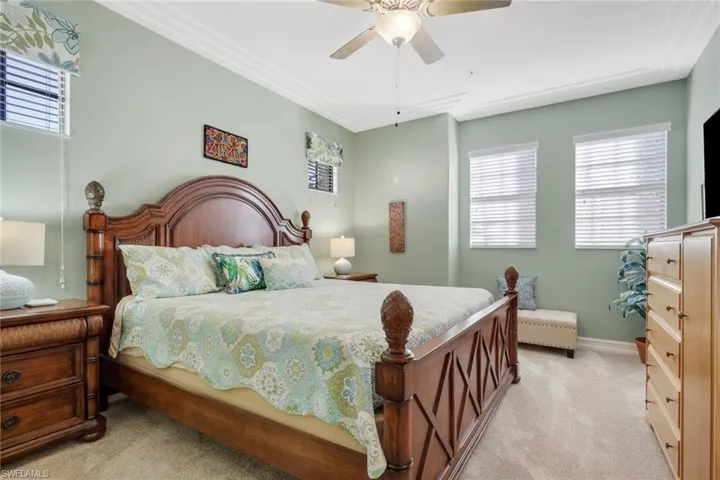Bedroom featuring multiple windows, light colored carpet, and ceiling fan