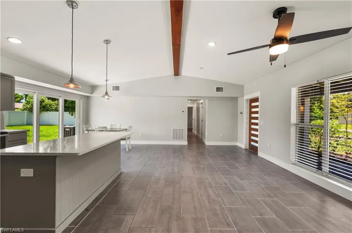 Kitchen featuring a center island, dark hardwood / wood-style flooring, ceiling fan, pendant lighting, and lofted ceiling with beams
