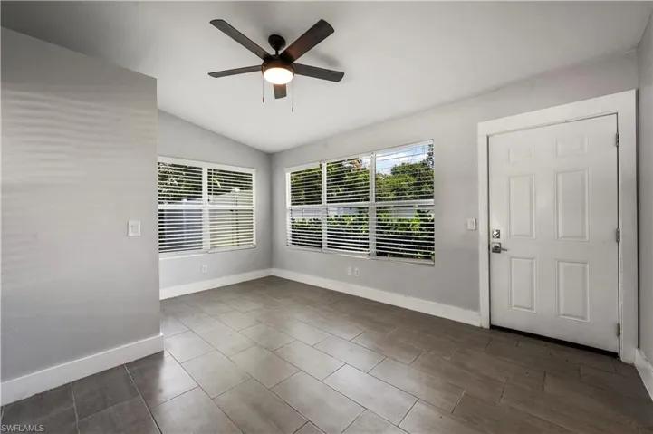 Unfurnished room with dark tile patterned floors, ceiling fan, and vaulted ceiling