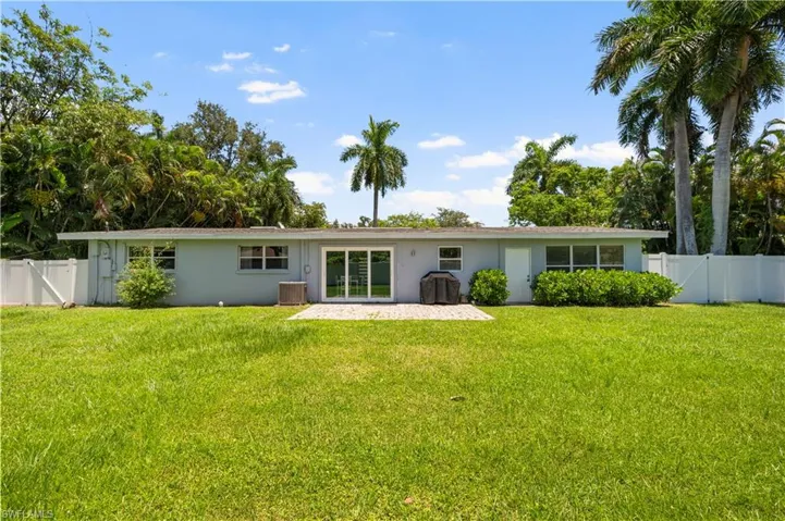 Rear view of house with a patio, cooling unit, and a lawn