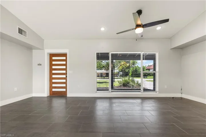 Tiled spare room featuring ceiling fan