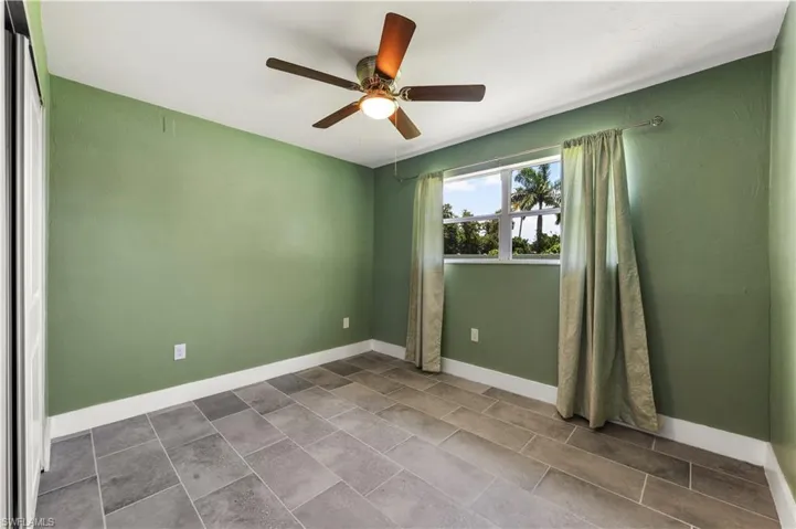 Tiled empty room featuring ceiling fan