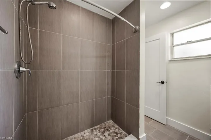 Bathroom with a tile shower and tile patterned flooring