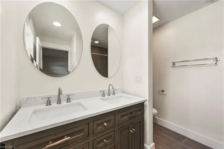 Bathroom with hardwood / wood-style flooring, double sink vanity, and toilet
