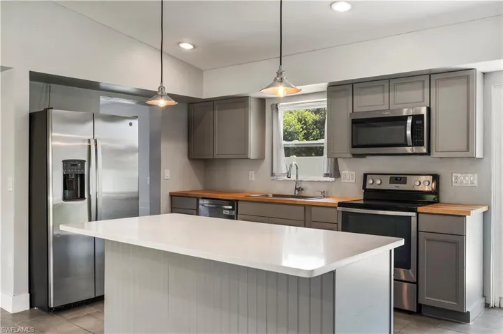Kitchen featuring decorative light fixtures, stainless steel appliances, sink, a center island, and gray cabinetry