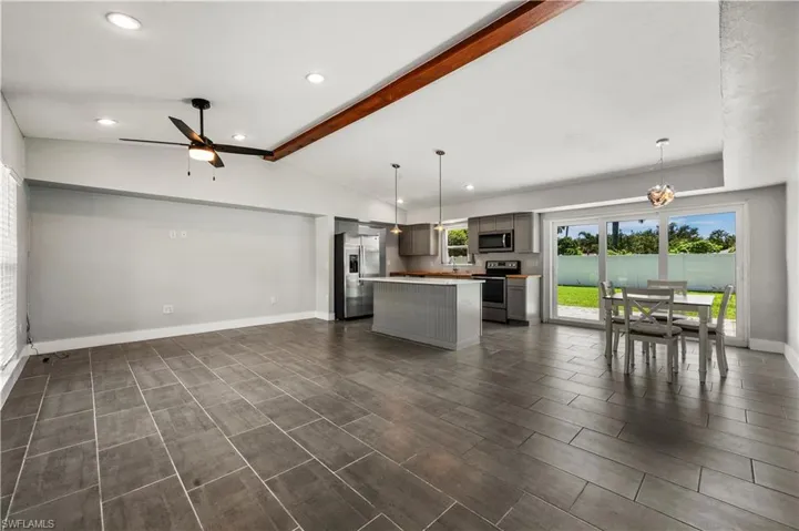 Kitchen featuring hanging light fixtures, appliances with stainless steel finishes, vaulted ceiling with beams, and a kitchen island