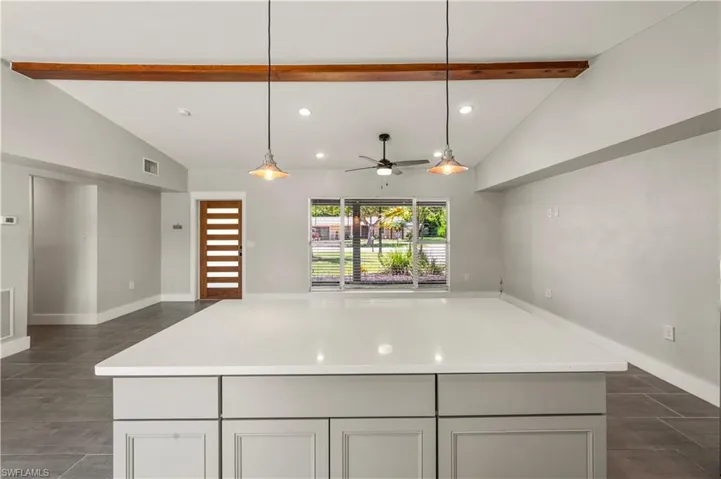 Kitchen with pendant lighting, lofted ceiling with beams, a center island, and ceiling fan