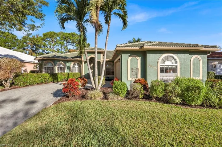 Ranch style home with stucco siding, a front yard, a tile roof, and driveway