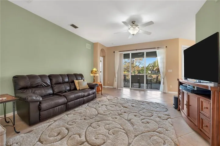 Living room featuring light tile patterned floors and a ceiling fan. Sliding doors to Lanai.