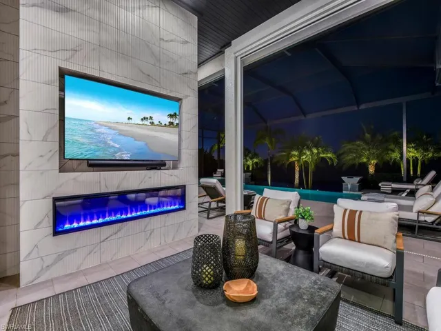 Custom Entertainment Nook - Lanai built-in entertainment center featuring an electric fireplace with heat capabilities & venting, textured porcelain tile to ceiling, recessed built-in 75" TV and Sonos sound bar