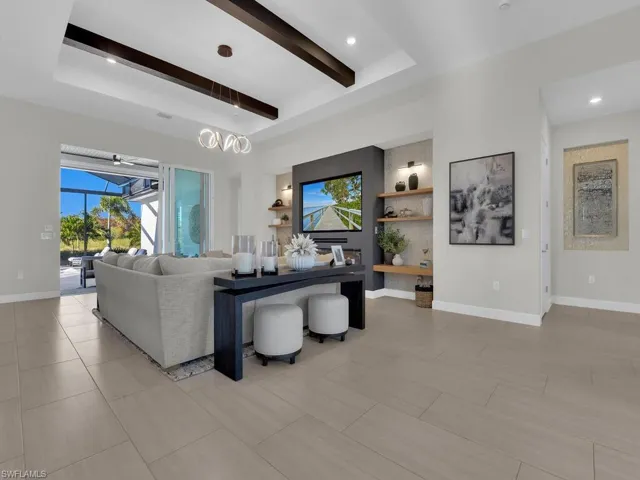 Modern built-in in great room featuring an electric fireplace with heat capabilities, floating custom shelving, recessed & mounted 83" TV & Sonos sound bar