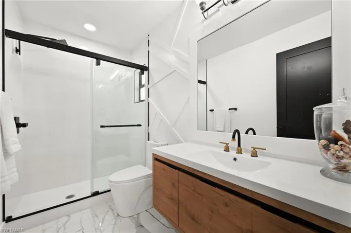 Bathroom with vanity, toilet, and shower with glass doors