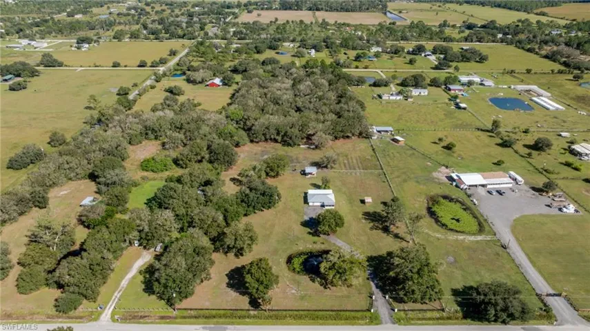 Expansive acreage featuring mature tree clusters, open pasture land, a private pond, and perimeter fencing