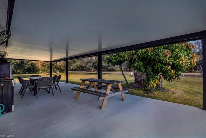 Covered concrete patio featuring a solid roof structure, dark-finished support pillars, and expansive outdoor area