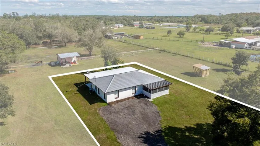 Single-story residence featuring a metal roof, screened porch, and expansive acreage