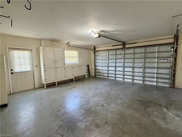 Spacious garage featuring a concrete floor, built-in cabinetry for storage, a rear access door, and a multi-panel garage door