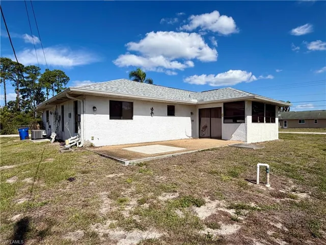 White stucco exterior featuring a gray shingle roof, screened porch, and concrete patio