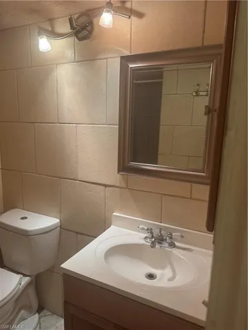 Bathroom featuring tile walls, vanity, and backsplash