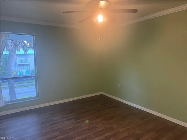 Spare room featuring ornamental molding, dark wood-style floors, and ceiling fan