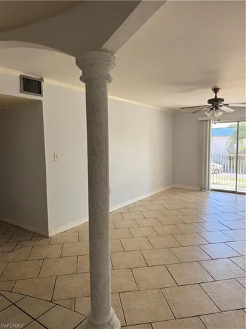 Unfurnished room with decorative columns, a ceiling fan, crown molding, and light tile patterned floors