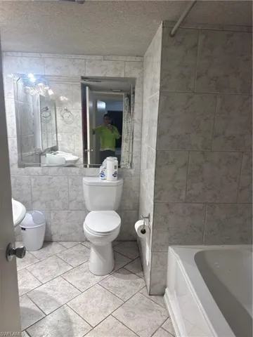 Full bathroom featuring tile walls, light tile patterned floors, a textured ceiling, shower / tub combination, and vanity
