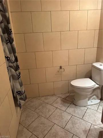 Full bathroom featuring tile walls, a shower with curtain, and tile patterned flooring