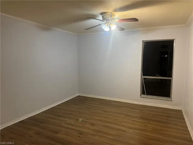 Unfurnished room featuring a ceiling fan, dark wood-type flooring, ornamental molding, and a textured ceiling
