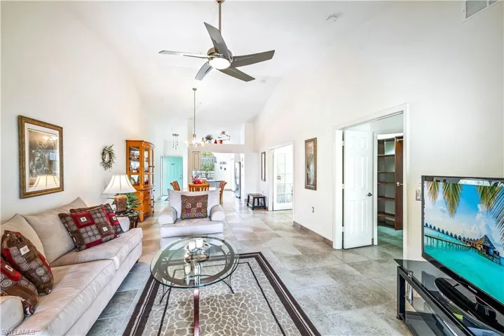 Living room with ceiling fan with notable chandelier and high vaulted ceiling