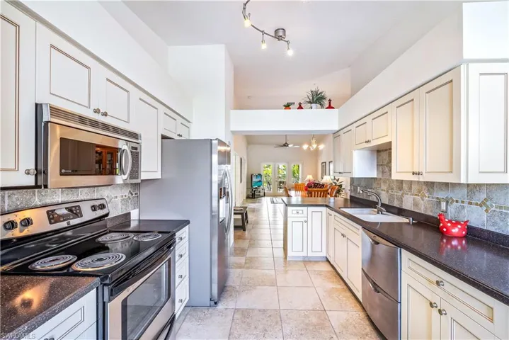 Kitchen featuring ceiling fan, sink, stainless steel appliances, tasteful backsplash, and kitchen peninsula