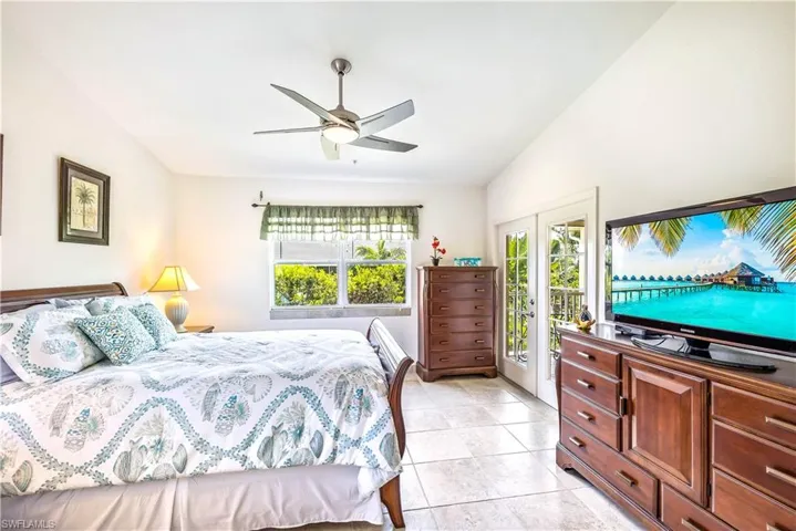Tiled bedroom featuring ceiling fan, access to exterior, french doors, and multiple windows