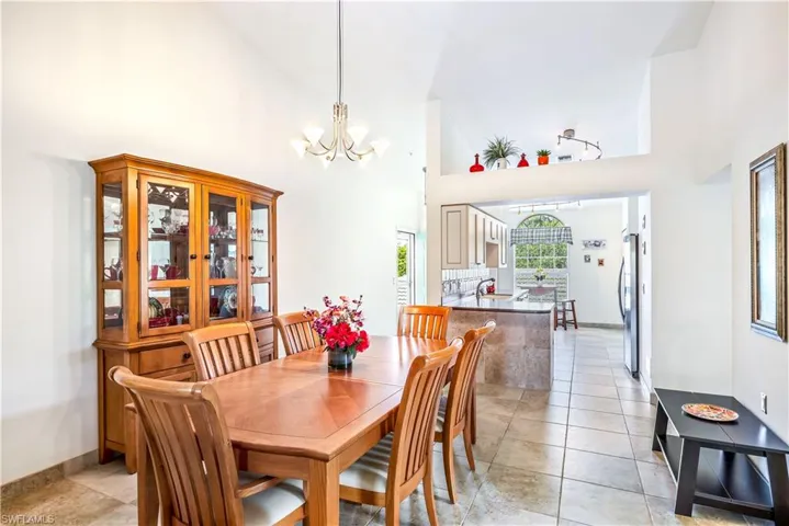 Tiled dining room featuring high vaulted ceiling and an inviting chandelier