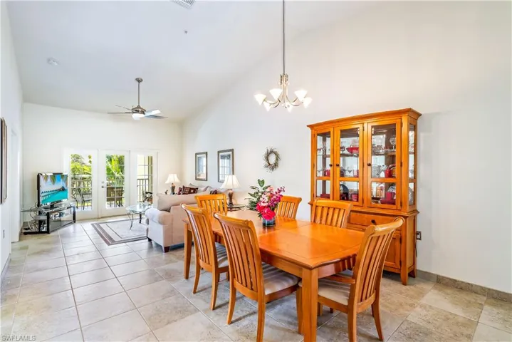 Tiled dining area featuring french doors, high vaulted ceiling, and ceiling fan with notable chandelier