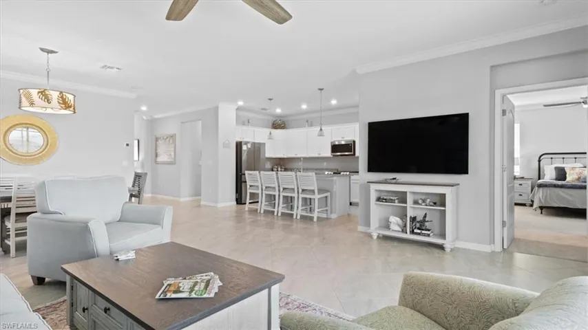Living room with ceiling fan, ornamental molding, and light tile patterned flooring