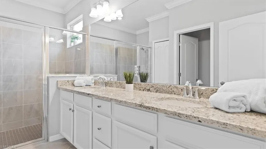 Bathroom with double vanity, a stall shower, and crown molding
