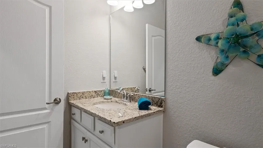 Half bathroom featuring a textured wall and vanity