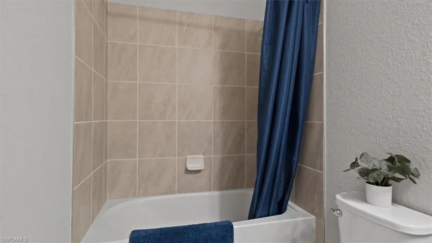 Full bathroom with a textured wall and shower / bath combo