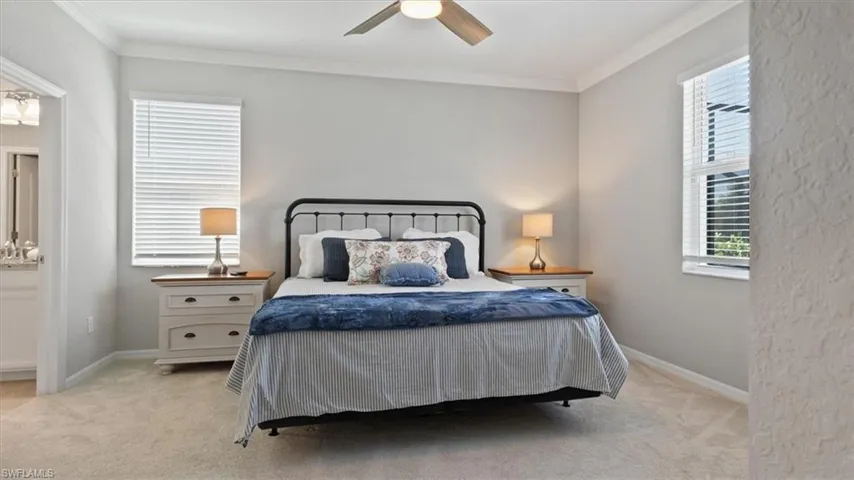 Bedroom featuring light colored carpet, ornamental molding, a ceiling fan, and ensuite bathroom