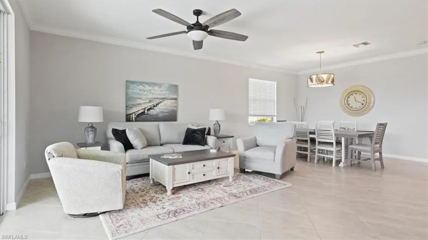 Living room featuring ornamental molding, a ceiling fan, and light tile patterned flooring