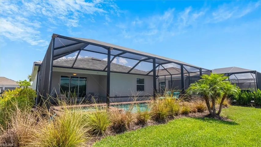 Rear view of house featuring a sunroom, a lanai, stucco siding, a patio, and a yard