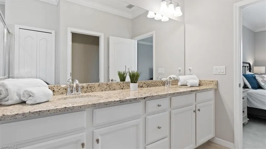 Full bathroom with connected bathroom, ornamental molding, double vanity, hanging lights, and a closet