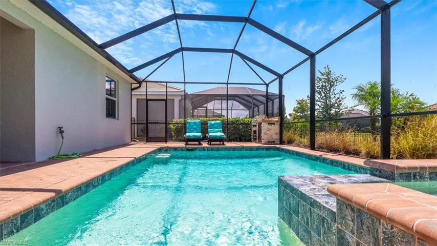 Outdoor pool featuring glass enclosure, a sunroom, and a patio