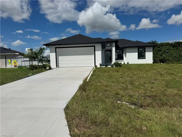 View of front of house with stucco siding, a front yard, an attached garage, and concrete driveway