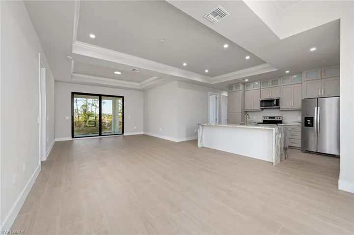 Unfurnished living room featuring sink, ornamental molding, and a raised ceiling