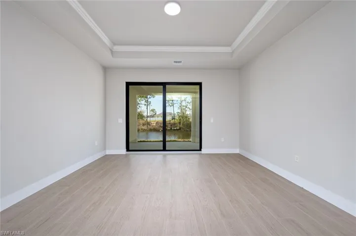 Unfurnished room with a tray ceiling, ornamental molding, and light wood-type flooring