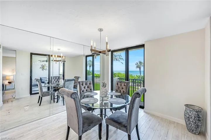 Dining area with expansive windows, light wood-style flooring, a chandelier, and a water view