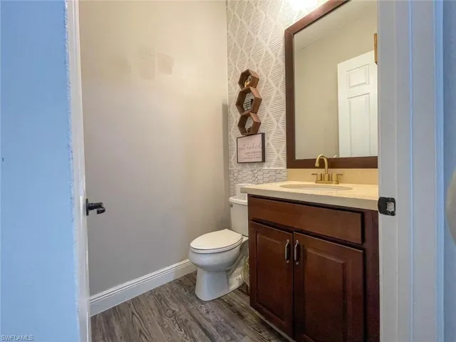 Bathroom with hardwood / wood-style floors, vanity, and toilet