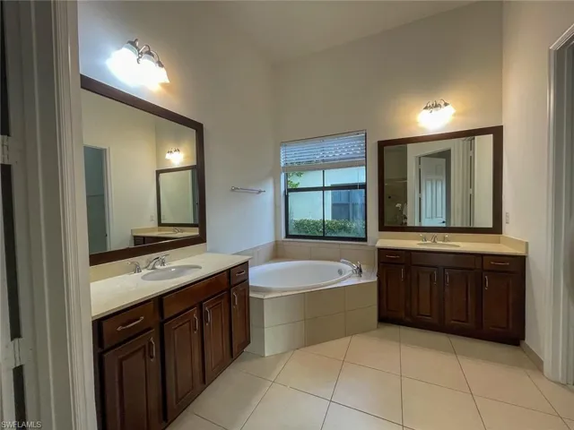 Bathroom with tile patterned floors, tiled bath, and vanity