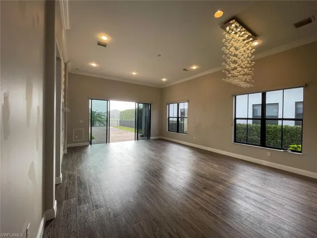 Spare room with a chandelier, dark hardwood / wood-style flooring, and crown molding